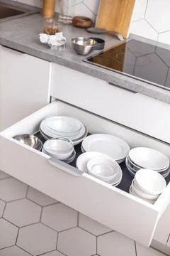 Comfortable white gray kitchen interior open box full of various crockery Stock-Fotos