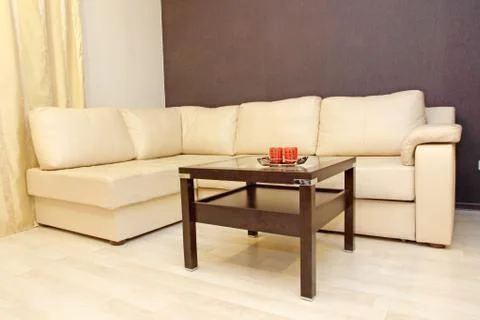 Comfortable white leather corner sofa with coffee table. Stock Photos