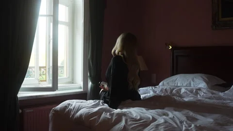 Comfortable woman on bed in front of window in a building Vidéo 264007988