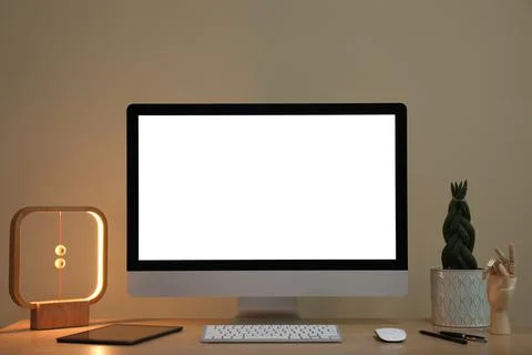Comfortable workplace with blank computer display on desk and plant near beig Stock Photos