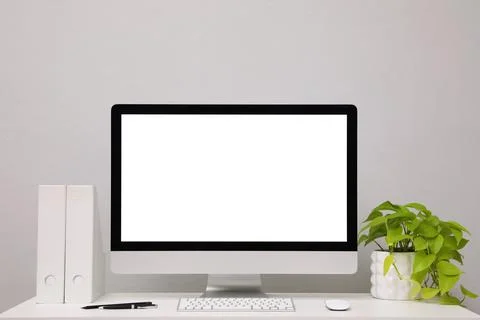 Comfortable workplace with blank computer display and plant on desk near ligh Stock Photos