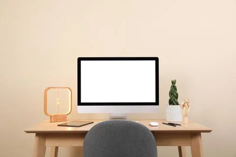 Comfortable workplace with blank computer display on desk and plant near beig Stock Photos