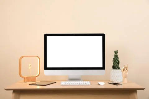 Comfortable workplace with blank computer display on desk and plant near beig Stock Photos