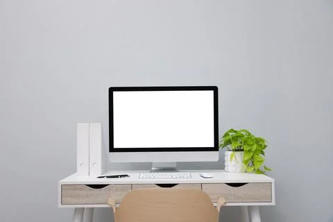 Comfortable workplace with blank computer display and plant on desk near ligh Stock Photos