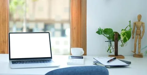 Comfortable workplace with laptop computer, coffee cup, notebook and housepla Stock Photos