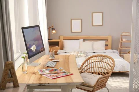 Comfortable workplace with modern computer near window in bedroom. Interior d Stock Photos
