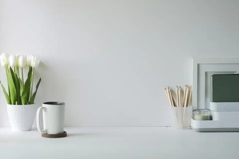 Comfortable workplace with picture frame, coffee, stationery and houseplant o Foto stock