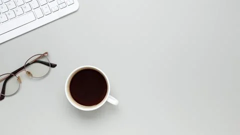 Comfortable workspace setup with coffee cup, keyboard, glasses supporting pro Stock Photos