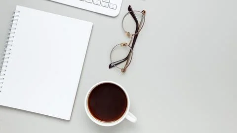 Comfortable workspace setup with coffee cup, keyboard, glasses and notebook s Stock Photos