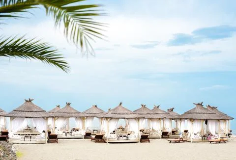 Comfotable tents with canopy and sofas on vip beach seascape Stock Photos