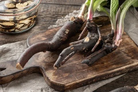 Comfrey root with comfrey tincture in the background Stock Photos