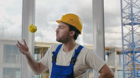 Comic fail. Builder drops the apple and pics it up. Stock Photos