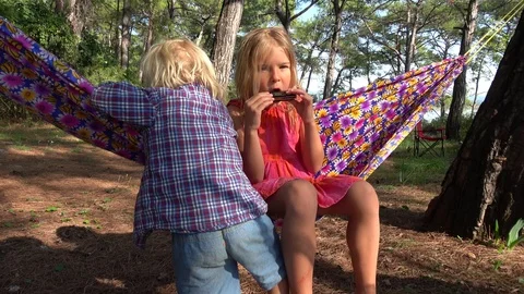 Comic fall of a small boy when his sister stands up from hammock Stock-Footage 120715450