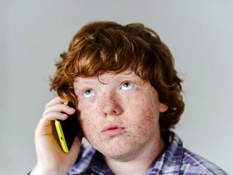 Comic freckled red-haired boy with mobile phone Stock Photos
