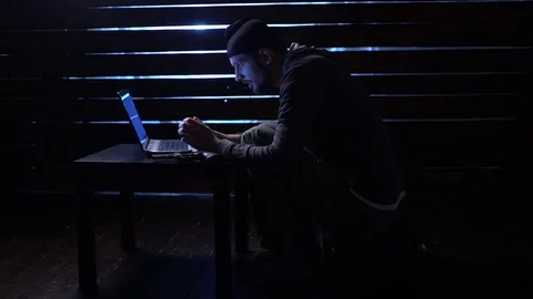 Comic funny hacker commits a cyber attack with a laptop and a gun in his hands Video stock 82551366