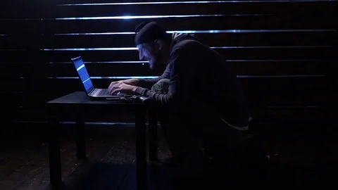 Comic funny hacker commits a cyber attack with a laptop and a gun in his hands Video stock 82551666