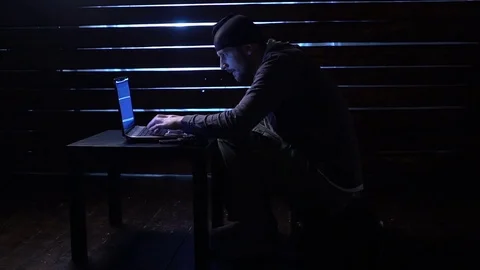 Comic funny hacker commits a cyber attack with a laptop and a gun in his hands Video stock 82552598