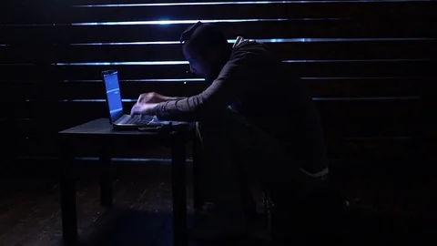 Comic funny hacker commits a cyber attack with a laptop and a gun in his hands Video stock 82554035