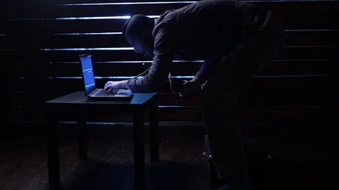 Comic funny hacker commits a cyber attack with a laptop and a gun in his hands Video stock 82555693