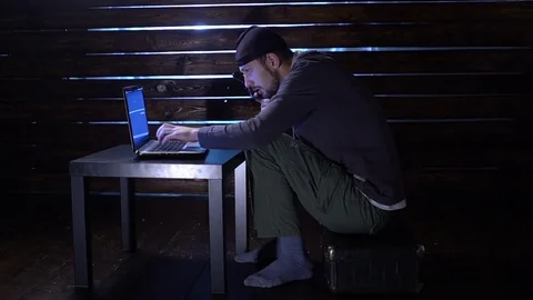 Comic funny hacker commits a cyber attack with a laptop and a gun in his hands Video stock 82557513