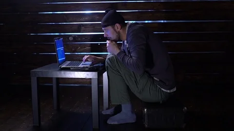 Comic funny hacker commits a cyber attack with a laptop and a gun in his hands Video stock 82558734