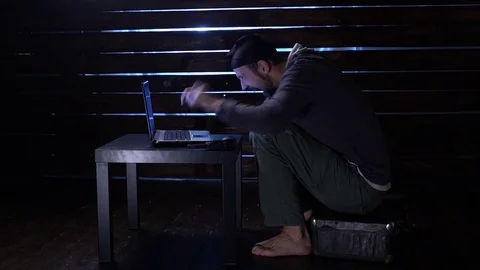 Comic funny hacker commits a cyber attack with a laptop and a gun in his hands Video stock 82567184