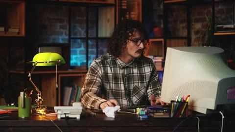 Comic male programmer working on retro computer and winking playfully, 90s style Video stock 321072102