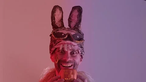 Comic man, young guy in cringe in scary bunny mask smiles menacingly, holdi.. Stock Footage 309051239