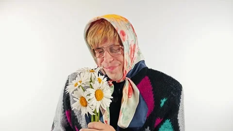 Comic portrait of a cross dressing man as old lady holding flowers 库存影片 340166995