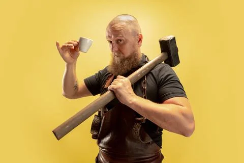 Comic portrait of muscular bearded bald man, blacksmith in leather apron or Stock Photos