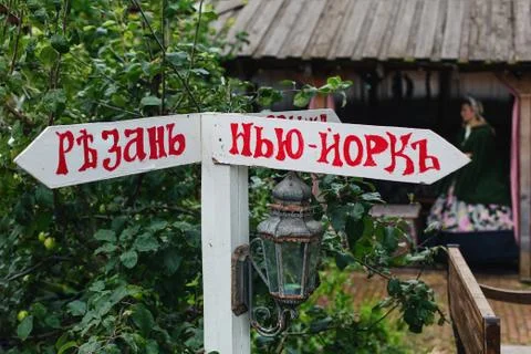 Comic wooden direction pointer to the left of Ryazan to the right of New York Stock Photos
