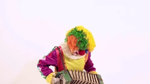 Comic young clown playing with harmonica pretending she can play it Stock-Footage 70509364