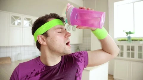 Comical man is drinking water from bottle after training and pouring on himself. Stock Footage 132116992