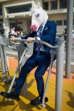 Comical man in elegant suit and funny mask does sport exercises Stock Photos
