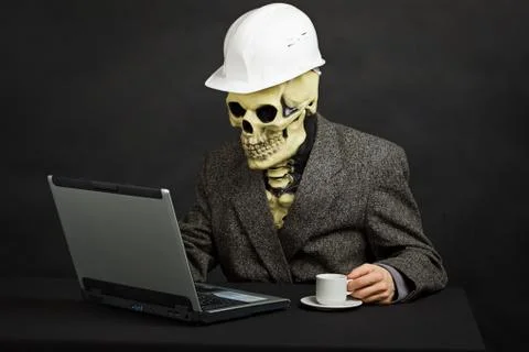 Comical man in helmet and skeleton mask with computer Stock Photos