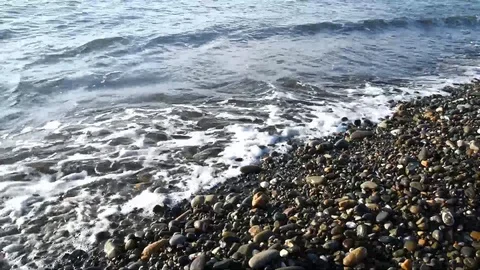 Coming waves on a stone beach with large round pebbles Stock Footage 121658488