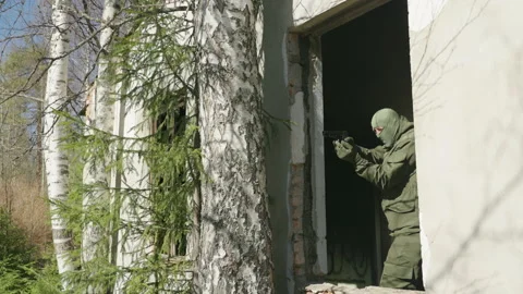 A commando in a balaclava shoots from the window of a building. Slow motion 库存影片 194705561