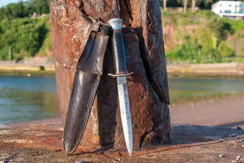 Commando dagger cleaning against a rusty post Stock Photos