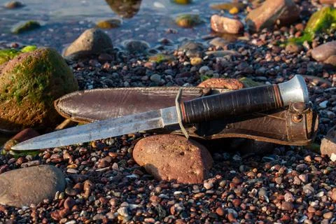 Commando dagger with sheath on a sandy shoreline Stock Photos