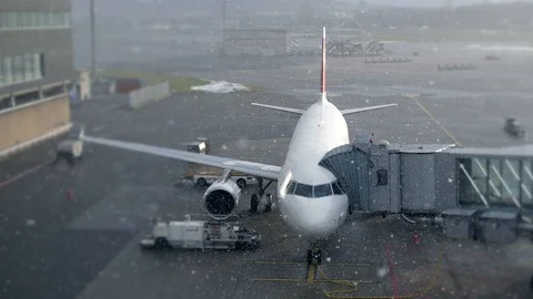 Commercial Airline Airplane Standing at Airport Terminal in Winter Snow Fall Stock Footage 87710756