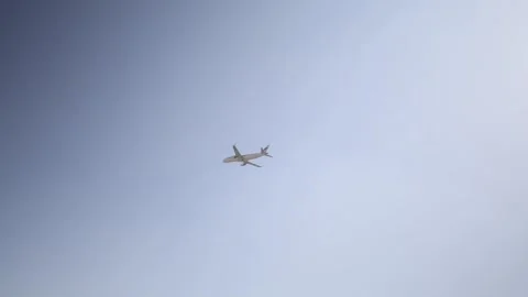 A commercial airplane soars through the sky, partially silhouetted against the b Stock Footage 303908005