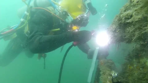 Commercial diver with diving helmet performing underwater welding Stock Footage