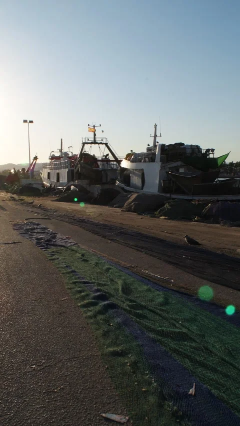 Commercial fishing nets spread on dock ground with trawler vessels Stock Footage 345735515