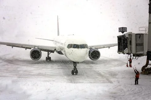 Commercial Jet Airplane Pulling up to Gate in Blizzard Snowstorm Stock Photos