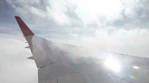 Commercial jet wing passing through clouds. Sun reflection. Stock Footage 62913231
