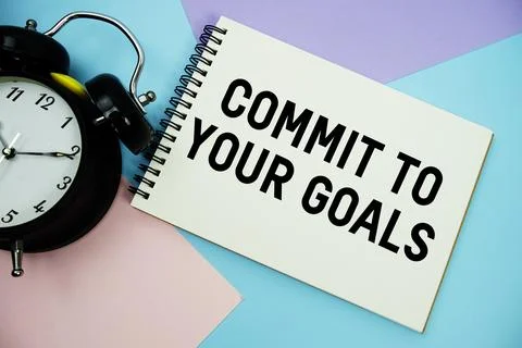 Commit To Your Goals text written on notepad with alarm clock flat lay on m.. Stock Photos