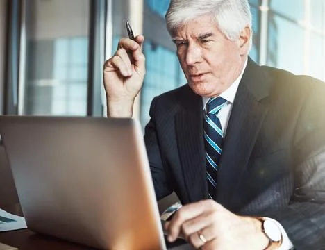 Commitment and dedication. a mature businessman working on his laptop in the Stock Photos