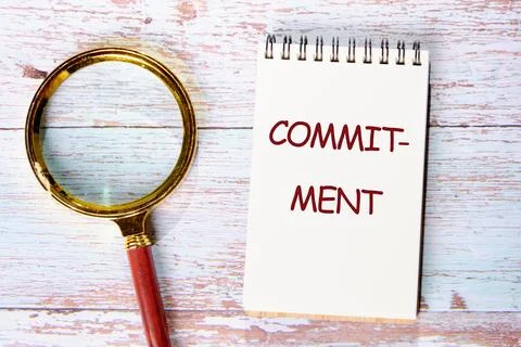 COMMITMENT Word Written in a notebook on old boards. Conceptual text Stock-Fotos