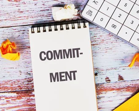 COMMITMENT Word Written in a notebook on old boards with a calculator in the  Stock-Fotos