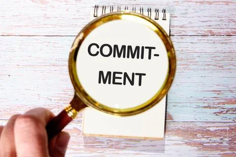 COMMITMENT Word Written through a magnifying glass in a notebook against the  Stock-Fotos